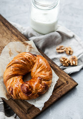 Fragrant pastry with nuts and a bottle of milk on a wooden board and a gray background