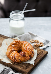 Fragrant pastry with nuts and a bottle of milk on a wooden board and a gray background
