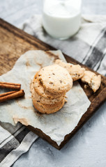Delicious pastry with cinnamon and a bottle of milk on a wooden board and a gray background