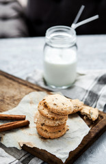 Delicious pastry with cinnamon and a bottle of milk on a wooden board and a gray background