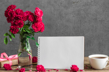 Still life with bouquet of red rose flowers, blank greeting card, cup of tea, gift box and buds. mock up