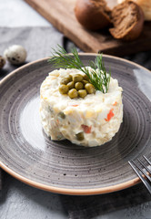 Olivier Russian with rye bread and quail eggs on a gray background