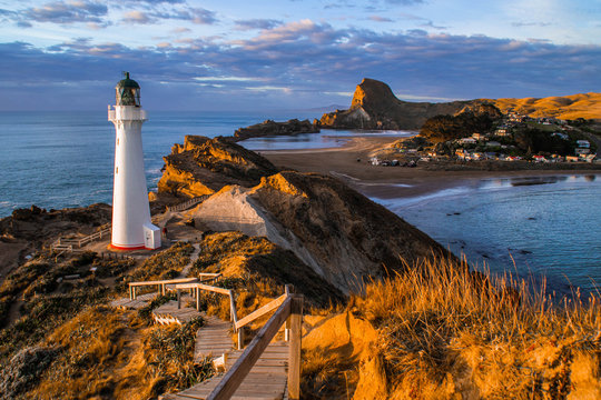 Panoramic scenic landscape view of the Castlepoint lighthouse in sunrise colours, white landmark, tourist popular attraction/destination in North Island, New Zealand. 