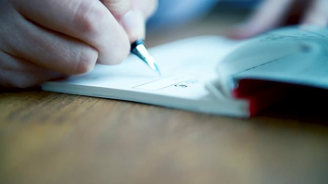 macro close-up detail of young business woman filling a banking cheque check writingwith luxury fountain pen the requested data in the luxury first class checkbook