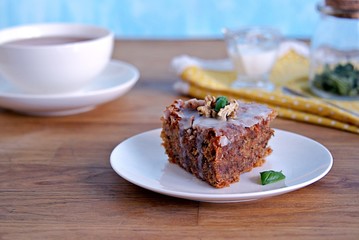 Dessert, a portion of carrot cake with walnuts and almonds on a white plate. Decorated with walnuts and icing.