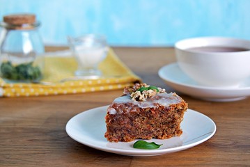 Dessert, a portion of carrot cake with walnuts and almonds on a white plate. Decorated with walnuts and icing.