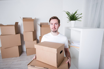 Young man with carton boxes in new apartment.
