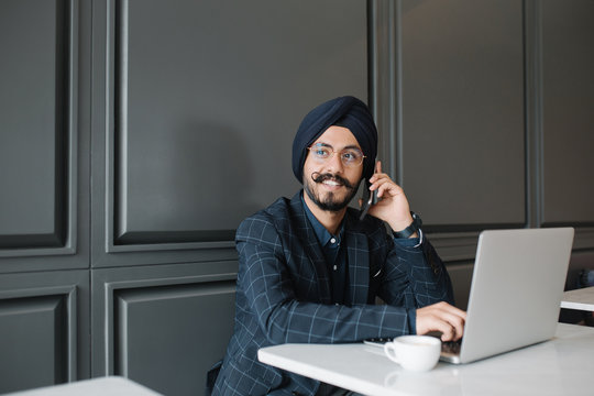 Smiling businessman talking on smartphone while sitting in cafe