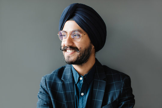 Smiling businessman standing near gray wall