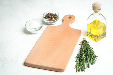 Fresh rosemary herb with oil and spices on a light background.