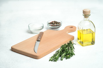 Fresh rosemary herb with oil and spices on a light background.