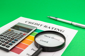 Credit rating with pen, magnifying glass and calculator.