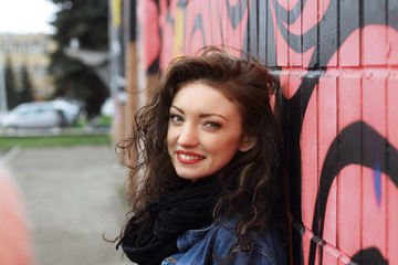 happy young woman standing by the wall.