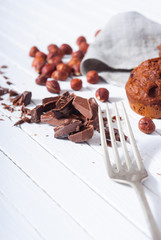 broken chocolate muffin and hazelnuts, fork on white wood table