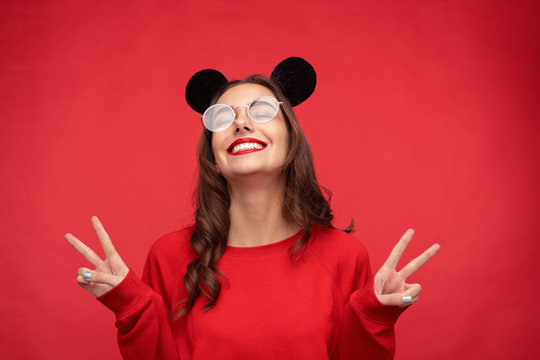 Playful teenage girl in mouse ears showing two fingers 