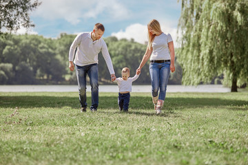 mother, father and play with their little son for a walk in the summer Park.