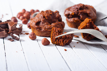 broken chocolate muffin and hazelnuts, fork on white wood table