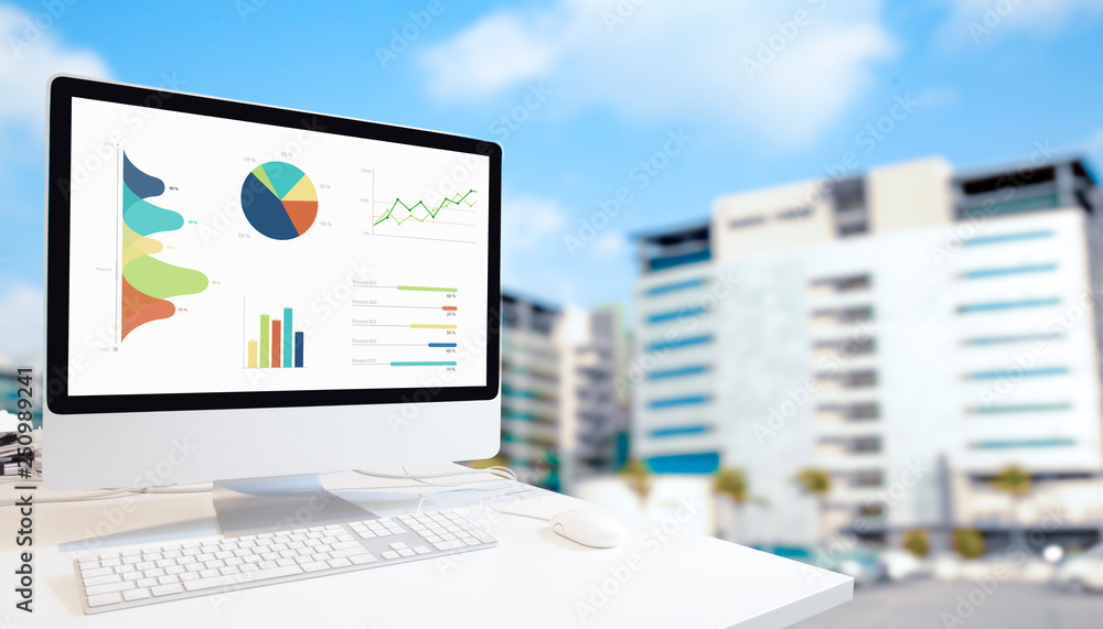Poster modern computer showing graphs, charts and diagrams on screen against blurred blue modern buildings 