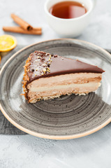 Caramel chocolate mousse cake on a gray plate with cinnamon and a cup of tea