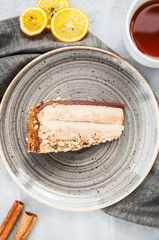 Caramel chocolate mousse cake on a gray plate with cinnamon and a cup of tea