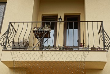 open black iron balcony on a brown wall with windows