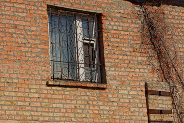 old window with iron bars on a brown brick wall