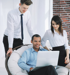 Obraz premium successful businessman with his assistants in a discussion of the information from the laptop.