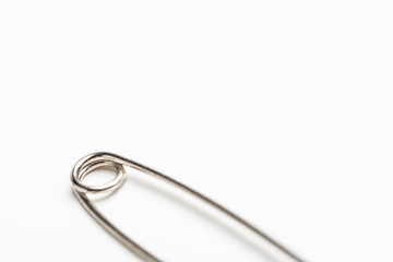 A close-up or macro shot of the spring coil of a common safety pin set on a white background.
