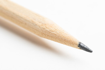 An extreme close-up or macro shot of the sharpened tip of a natural color pencil set against a plain white background.