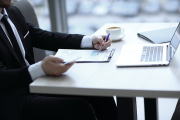 closeup.businessman checking financial statement,sitting at the Desk