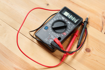 digital multimeter and wiring on wooden table. special tools of technician for work with circuit...