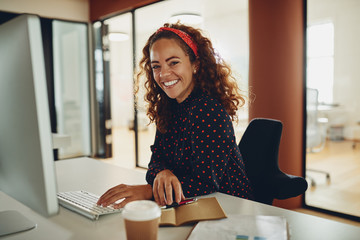 Smiling young businesswoman working on her office computer