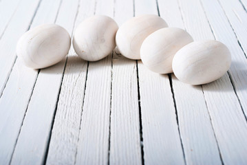 Fototapeta na wymiar white painted wooden eggs on bright wood table background