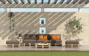 Garden with pallet sofa with stone wall on background