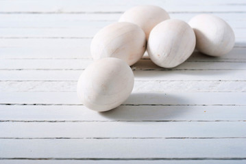 white painted wooden eggs on bright wood table background