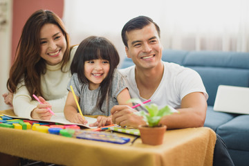 Fototapeta premium Family time Daughter laughing enjoying playing with her parent on the table in front of sofa at home.