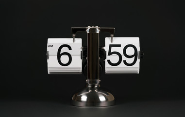Isolated vintage flip clock on black background at six o'clock and fifty nine minutes