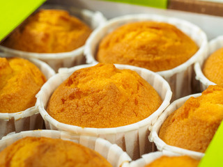 Freshly baked cinnamon mini muffins for breakfast in the morning.  Green Paper holder on a wooden background.