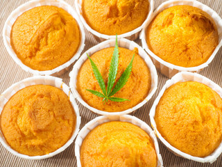 Freshly baked cinnamon mini muffins with cannabis and buds of marijuana on the table. Concept of cooking with cannabis herb. Treatment of medical marijuana for use in food.