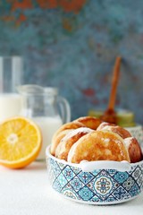 Yeast pancakes in powdered sugar with milk and honey on a light background. Yeast fritters for Sunday breakfast