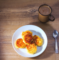 Cottage сheese pancakes with fried crust with with spun and coffee on wooden background