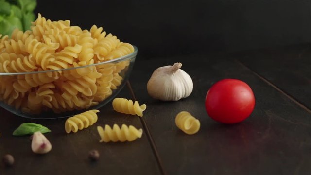 pasta ingreidents panning shot.fusilli cherry tomatoes basil garlic mushroom on wooden table