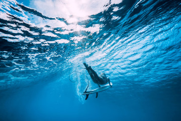 Attractive surfer woman dive underwater with under wave in blue ocean.