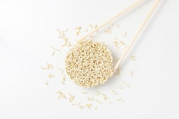 Overhead view of raw instant Asian egg noodles shaped in the form of a circle and chopsticks