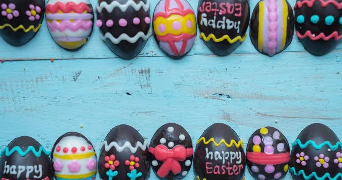 Stop motion of decorative chocolate easter eggs and happy easter text on wooden table. Shot in 4k resolution