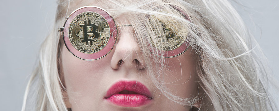 Beautiful young blond woman with red lips in glasses with bitcoins on a white background. Cryptocurrency concept