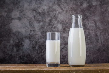 Glass and Bottle of fresh milk. Bottle with milk and glass of milk on wooden table.