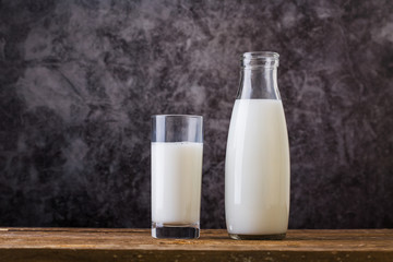 Glass and Bottle of fresh milk. Bottle with milk and glass of milk on wooden table.