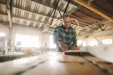 Fototapeta na wymiar Senior carpenter manufacturing wooden products