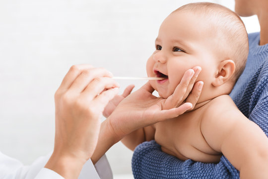 Doctor pediatrician examining throat of newborn baby
